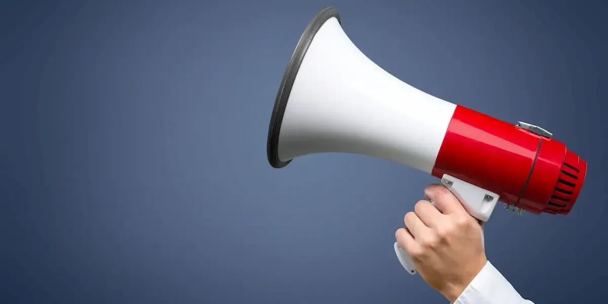Hand holding a megaphone pointed silently, symbolizing stealth marketing and quiet communication.